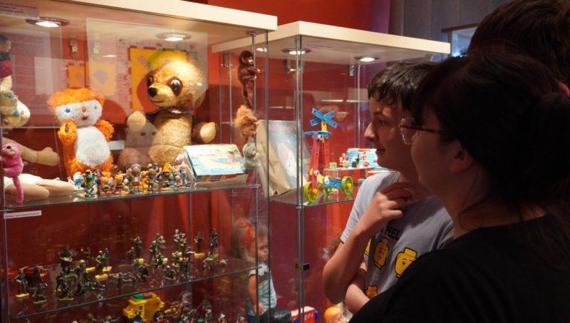 Kobieta i chłopiec na wystawie oglądają gablotę z zabawkami