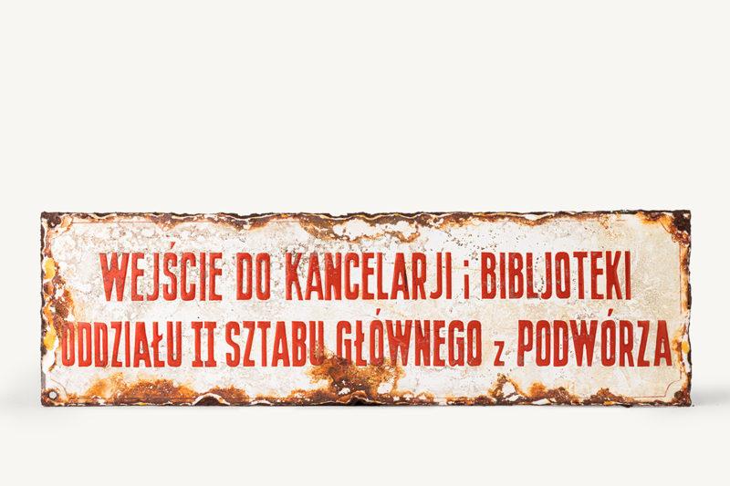 Tabliczka informacyjna Tabliczka żelazna, zewnętrzna, informacyjna z napisem "wejscie do kancelarii i biblioteki oddzielu II Sztabu Glownego z pódworza"