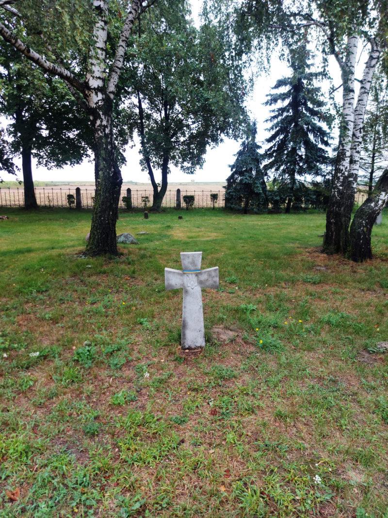 20220821_102016 Ukraiński Cmentarz Wojskowy w Kaliszu, 2023 r. Widok betonowego krzyża w ziemi, a w tle brzozy