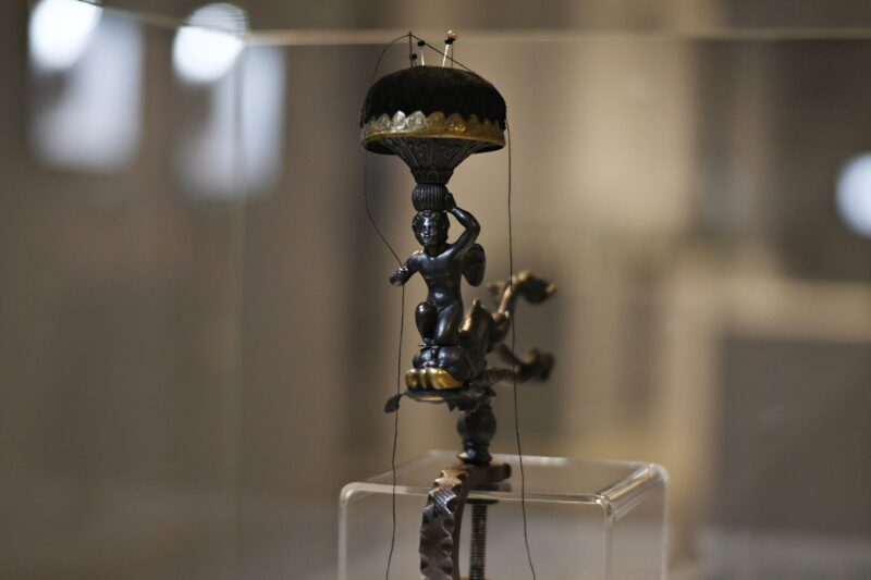 Przyrząd do szycia ze spinaczem w kształcie delfina, amorkiem podtrzymującym poduszkę na igły oraz z imadłem do mocowania, po rekonstrukcji, Królewska Odlewnia Żelaza w Gliwicach, odlew żeliwny, montowany, mosiądz, 23,8x13,5 cm, ok. 1830 r.