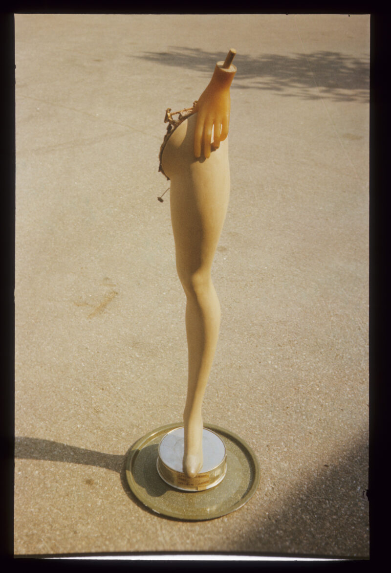 Władysław Hasior "Notatnik fotograficzny", z lat 1965-1998, z serii "Montaże". Noga manekina na małym podeście, od góry złapana przez dłoń z manekina.