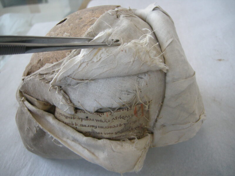 DSCN4598 Relikwia podczas konserwacji po zdjęciu dekoracji z XIX w. Głowę okrywa tkanina atłasowa (zielona i pąsowa). Relikwii towarzyszy pergaminowa ceduła z inskrypcją: „Caput XI Millium Virginum”