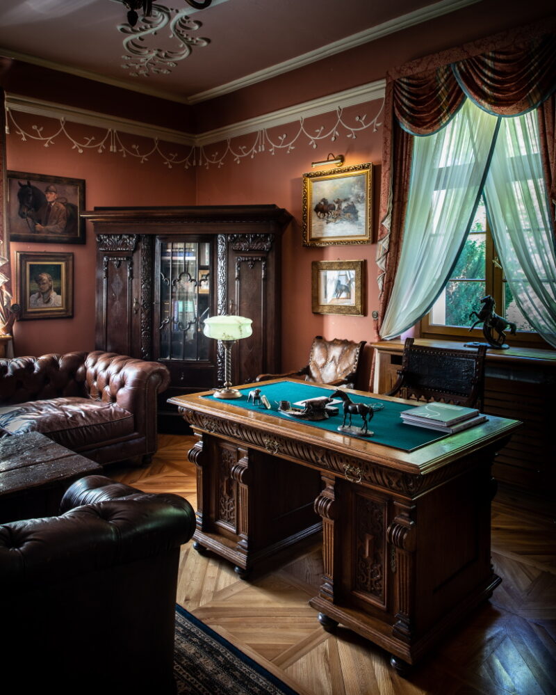 maslow_V9A2107_1024 Jeden z pokoi dworu. Gabinet z drewnianym biurkiem. Obok dwie sofy, a za nimi szafa.