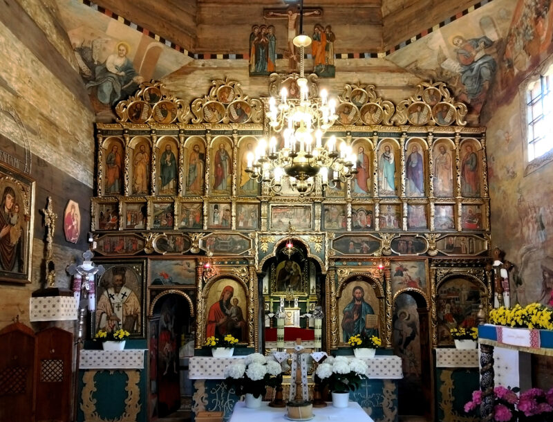 Wnętrze cerkwi w Chotyńcu. Ukazuje ikonostas. Z sufitu wisi żyrandol.