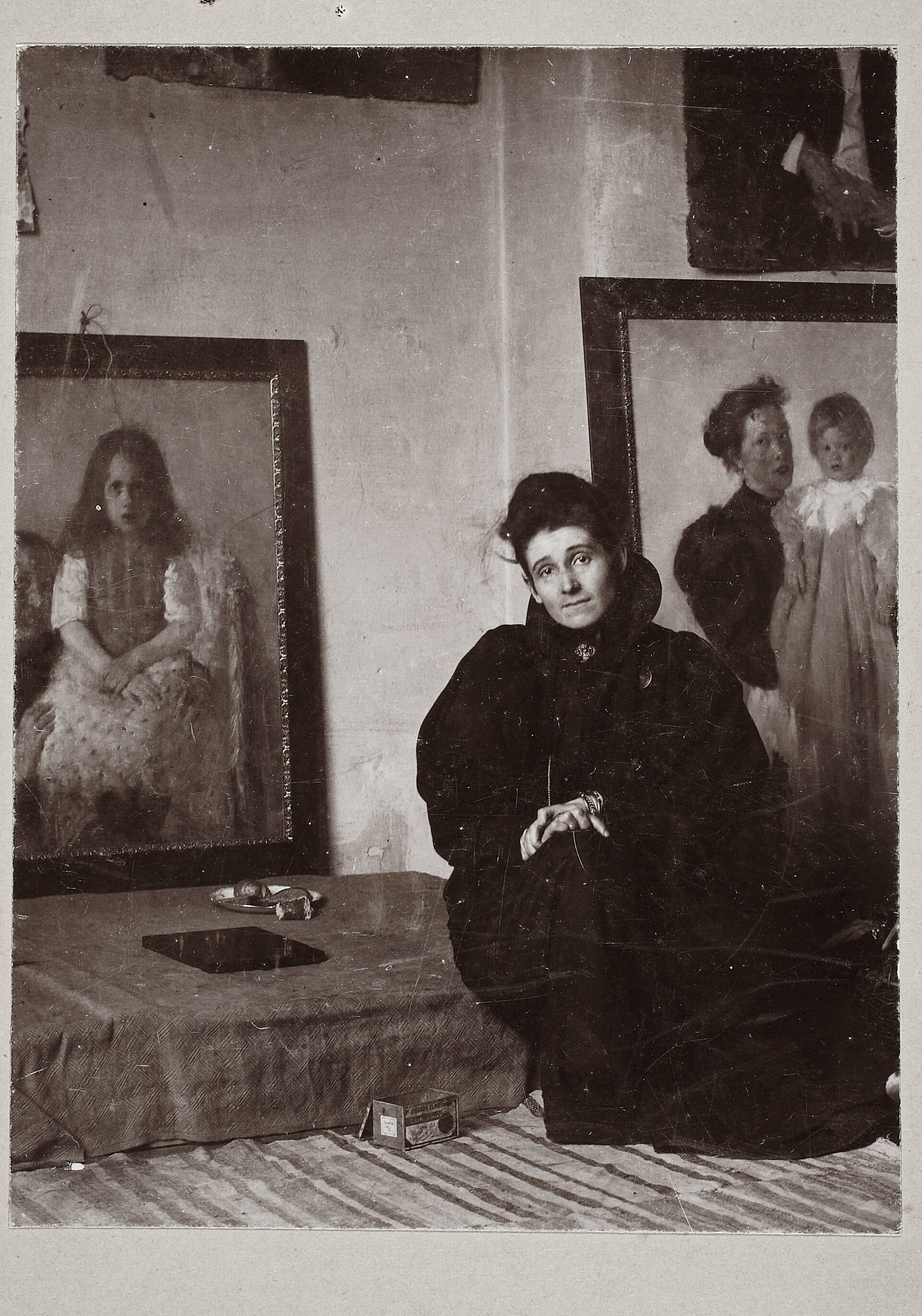 Olga Boznańska w pracowni przy Georgenstrasse w Monachium. Po lewej fragment obrazu "Dziewczynka z piastunką" z ok. 1896 r., po prawej "Matka z dzieckiem" z 1893 r.